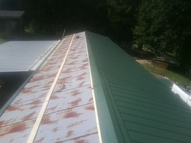 Old rusted panels beside newly installed green metal roofing — Wind Damage Roof Repair by Roofing Brothers in Pomeroy