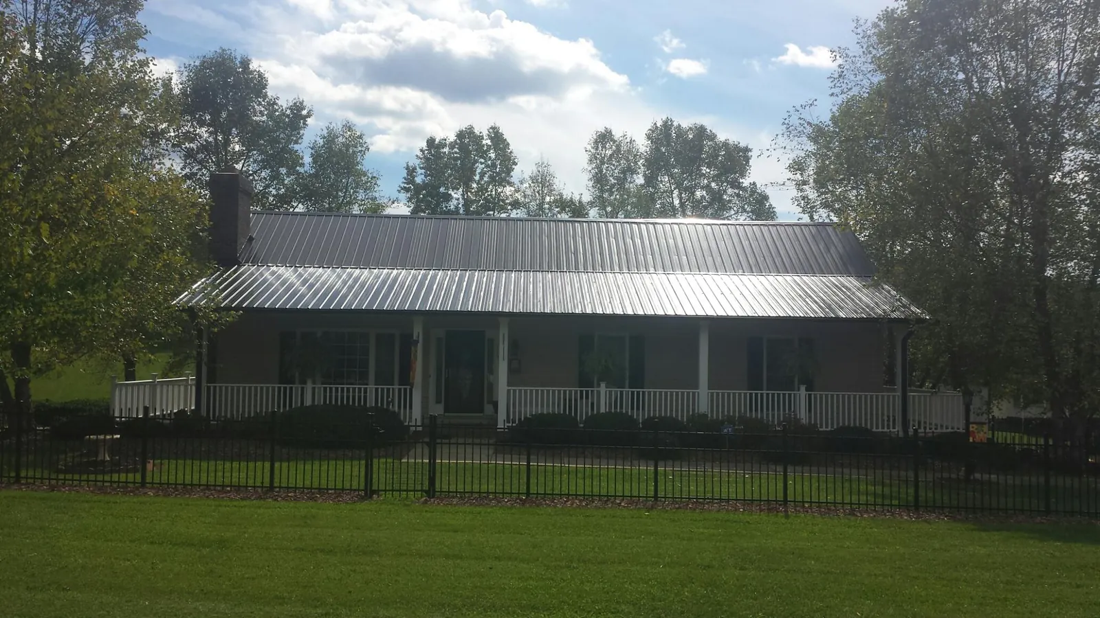 Gray metal roof on a brick ranch with a full width front porch — Gutter Guard Installation work by our crew in Pomeroy