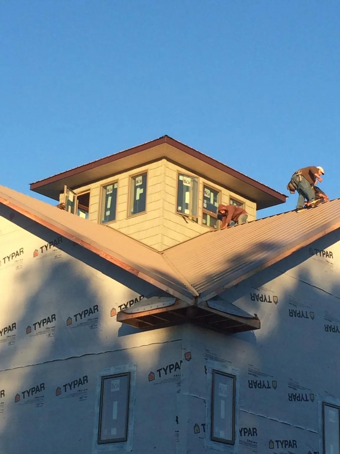 Roofers working around a rooftop cupola on a new metal roof at sunset — Roof Waterproofing in Pomeroy by Roofing Brothers
